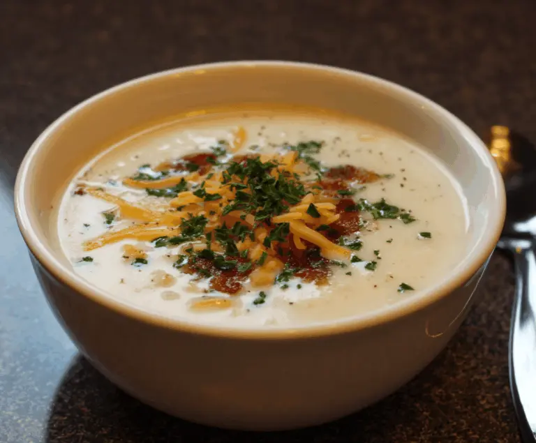 Creamy Outback Steakhouse Potato Soup with melted cheese, bacon bits, and fresh herbs in a bowl
