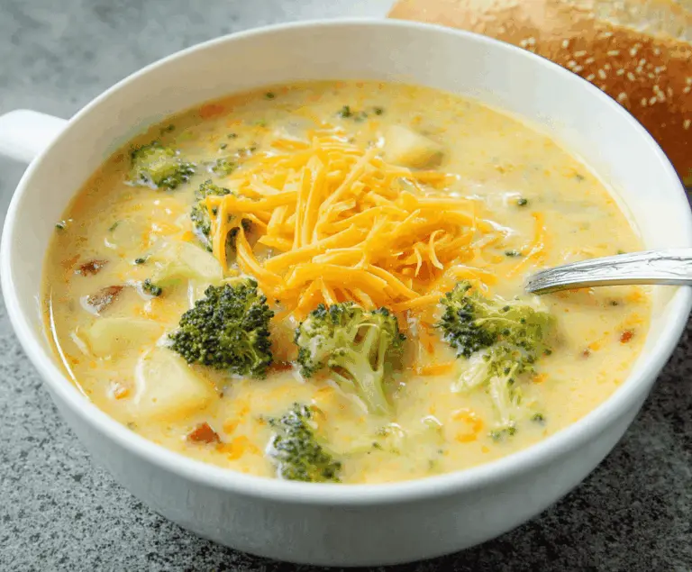 Creamy broccoli, potato, and cheese soup served in a bowl with fresh broccoli florets on top, perfect for a cozy meal.