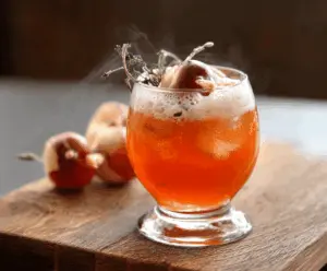 Spooky Poisoned Apple Cider in a Halloween-themed glass with cinnamon sticks and apple slices, perfect for a festive spooky season drink