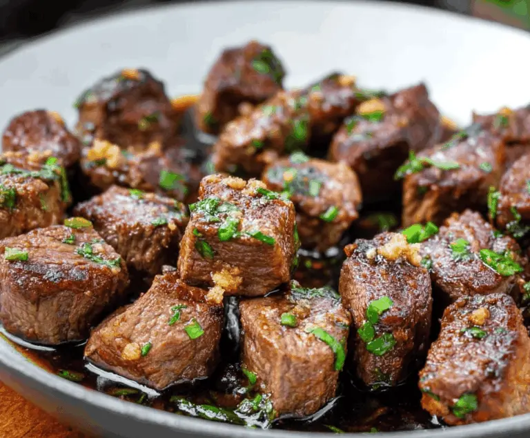 Juicy steak bites made with tender stew meat served on a plate with herbs and dipping sauce