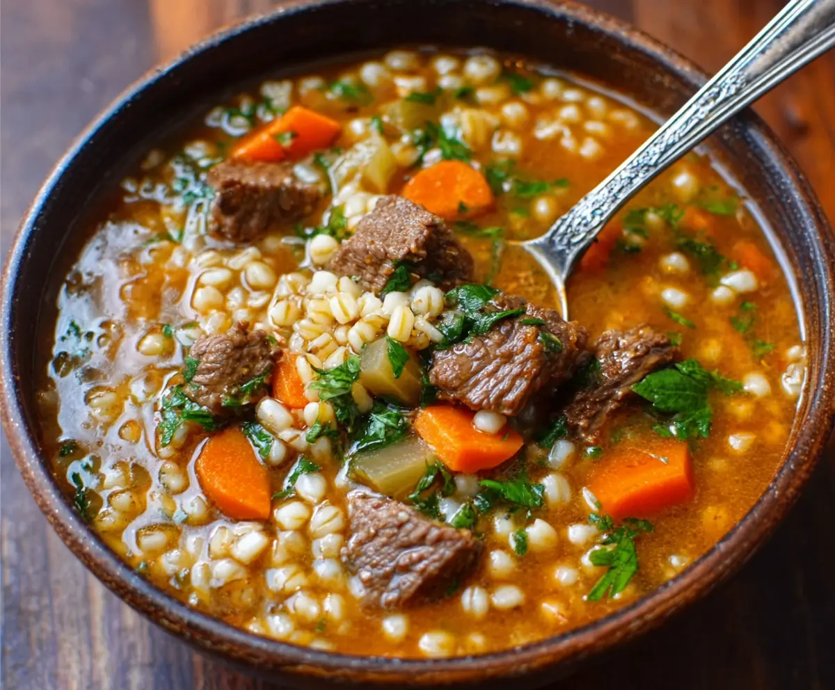 Hearty beef and barley soup with fresh vegetables in a rustic bowl, perfect for a comforting meal.