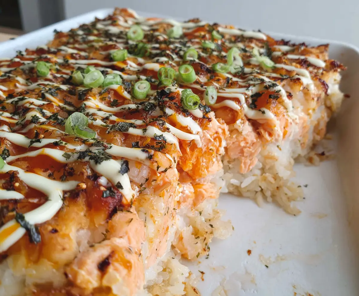 Delicious spicy salmon sushi bake topped with fresh herbs and crispy rice crust.
