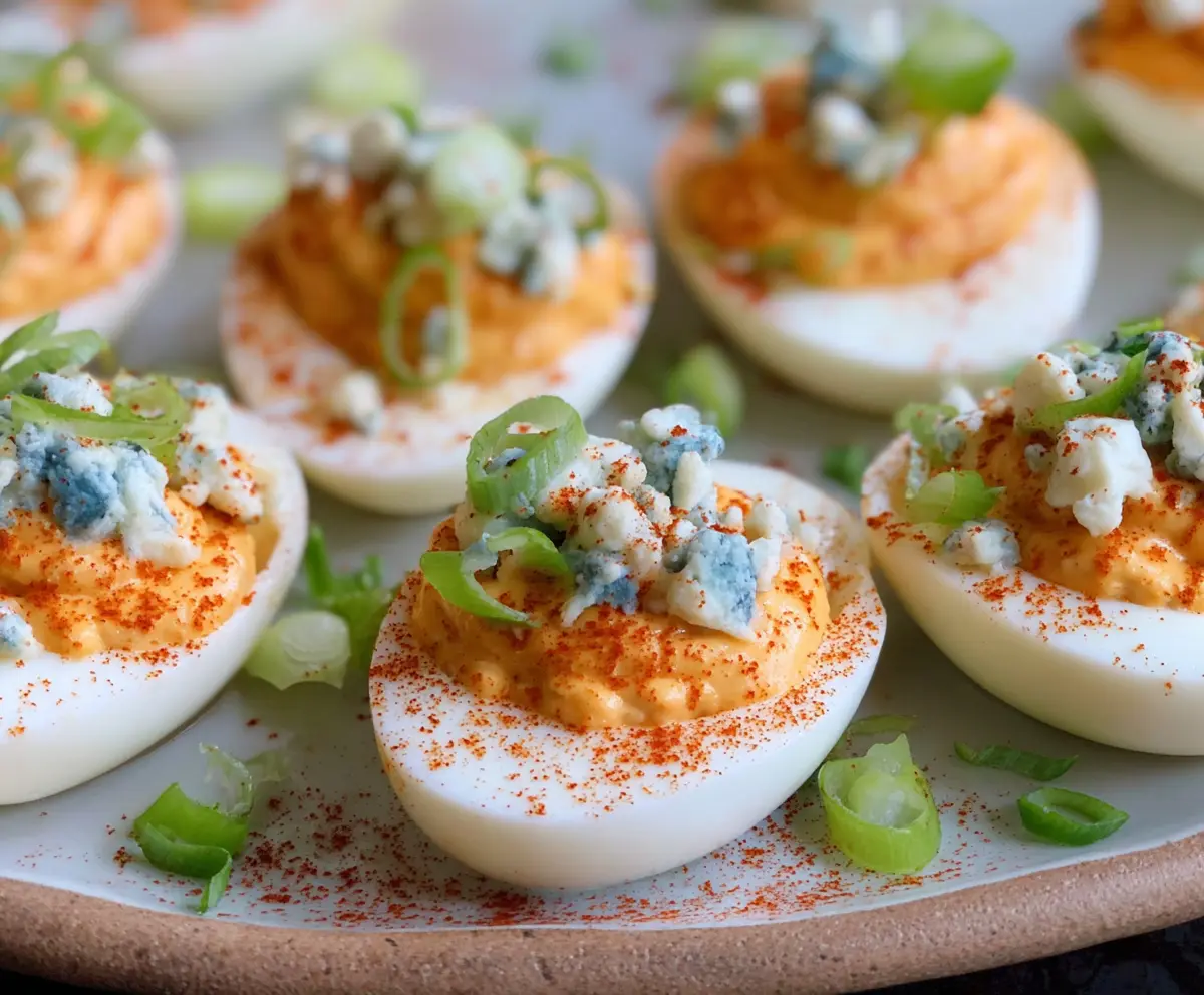 Buffalo Blue Cheese Deviled Eggs on a serving platter with crispy garnish