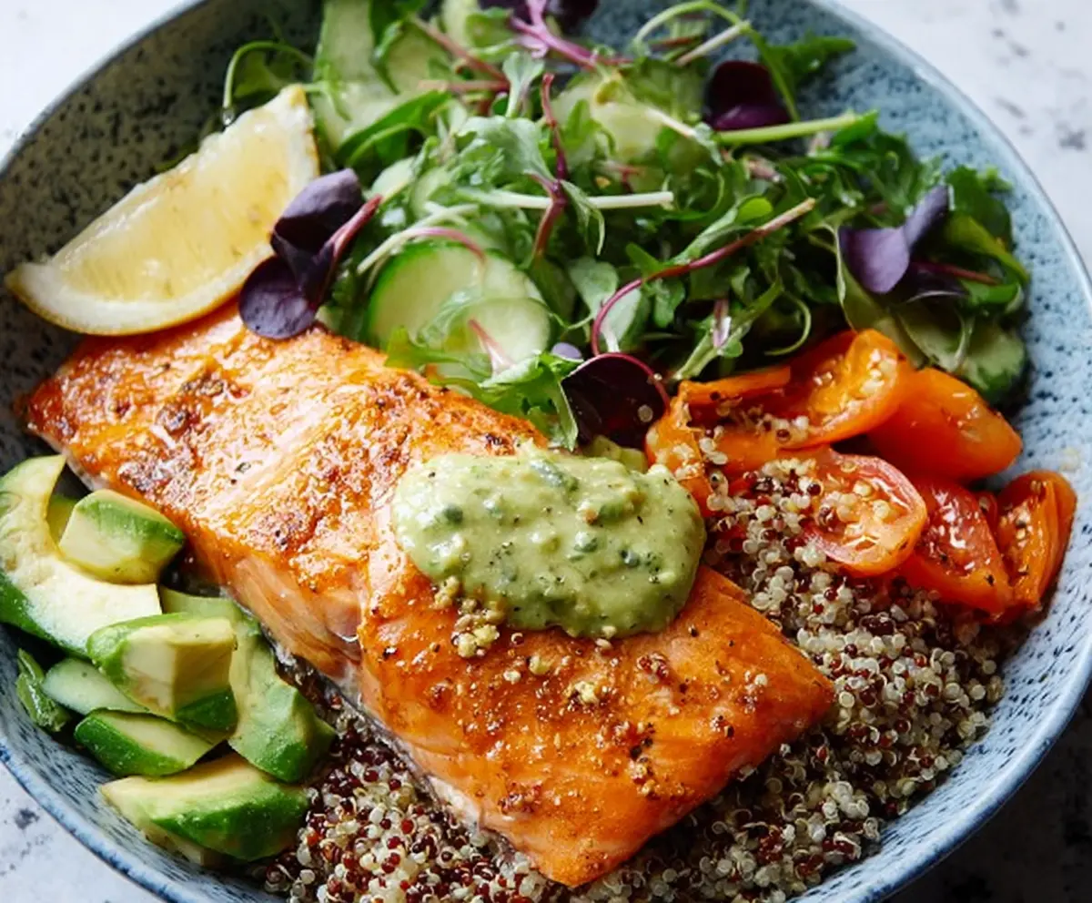 Healthy salmon and quinoa power bowl with fresh vegetables and herbs, perfect for a nutritious meal.