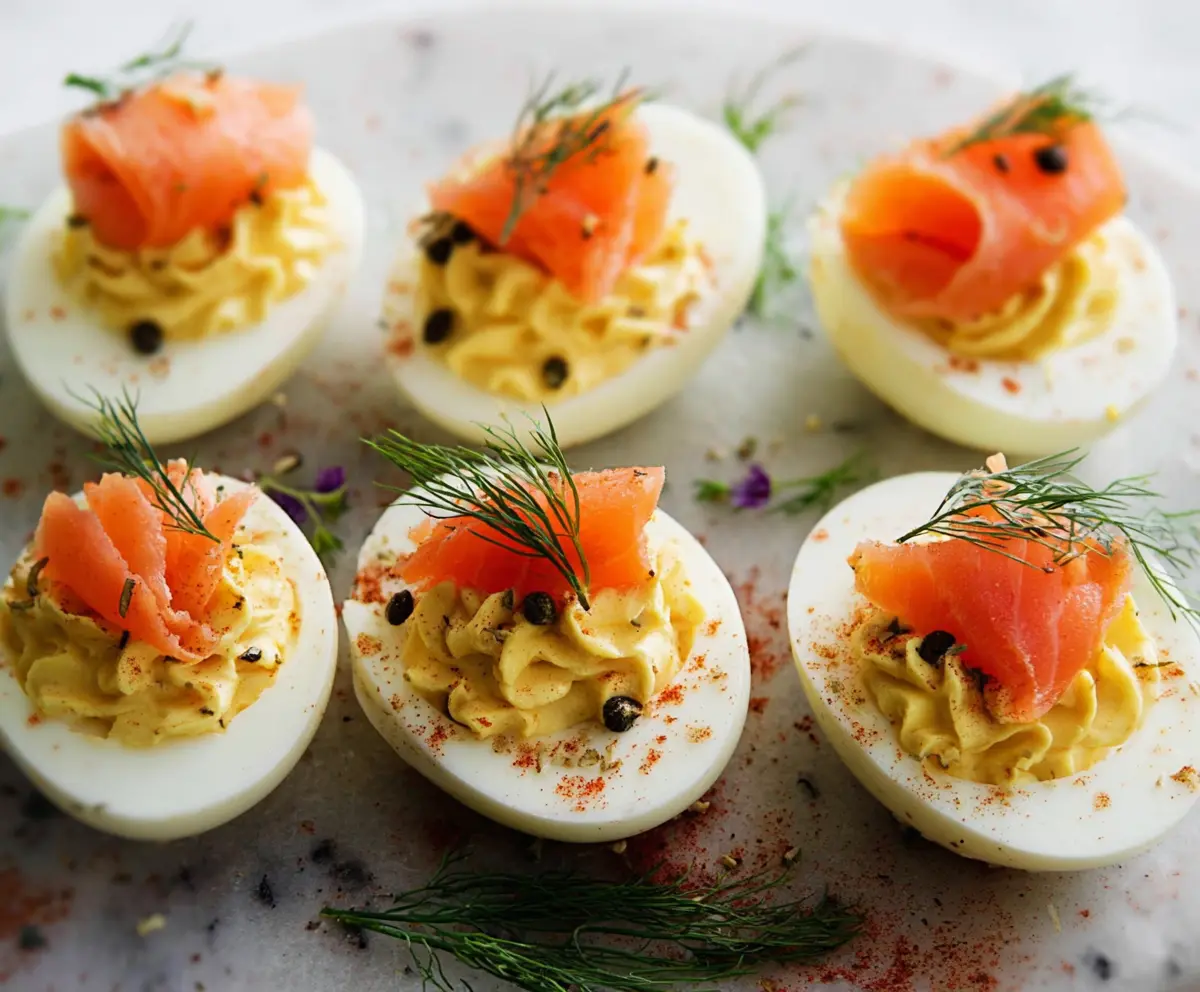 Delicious smoked salmon deviled eggs garnished with fresh herbs on a white plate.