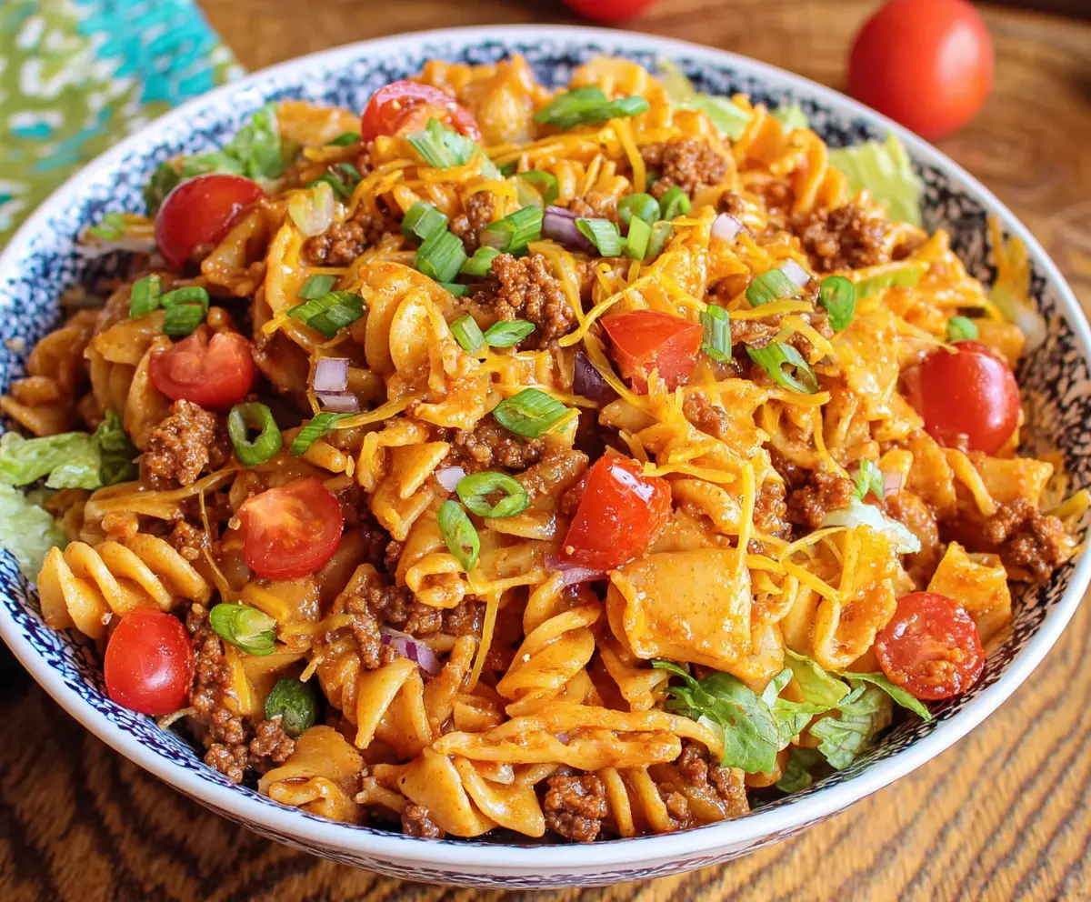 Delicious Taco Pasta Salad with seasoned beef, fresh vegetables, and creamy dressing in a colorful bowl.